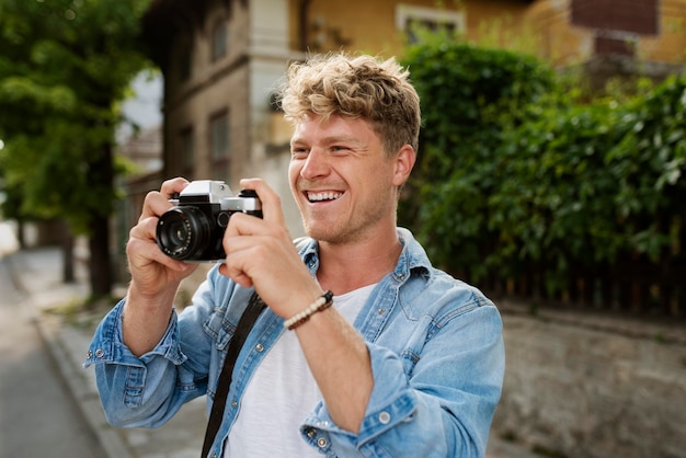 Uomo sorridente con colpo medio che tiene la macchina fotografica