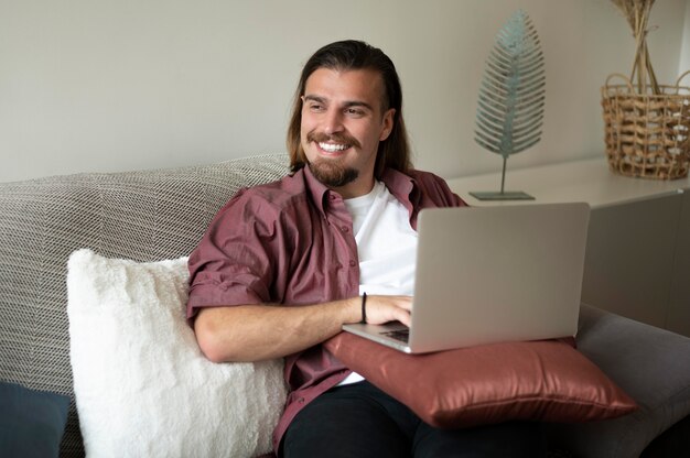 Uomo sorridente con colpo medio con laptop