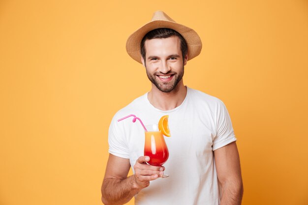 Uomo sorridente con il cocktail che guarda macchina fotografica