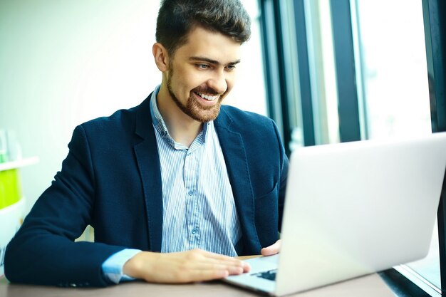 Uomo sorridente dei pantaloni a vita bassa di giovane modo nel caffè della città durante l'ora di pranzo con il taccuino in vestito