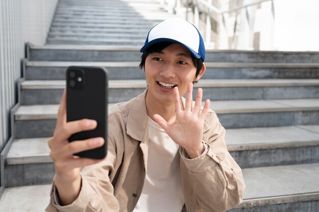 Uomo sorridente del colpo medio che saluta al telefono