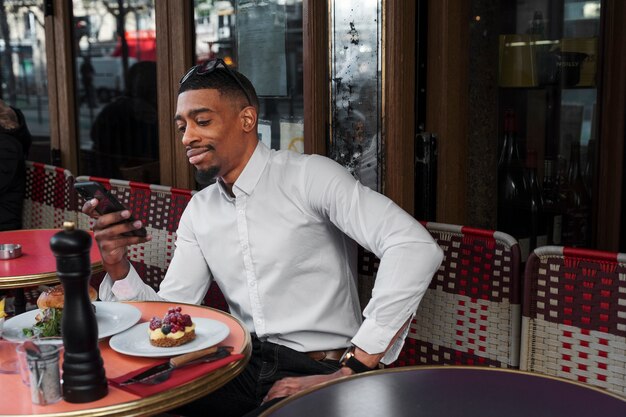 Uomo sorridente del colpo medio che si siede al bistrot