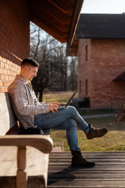 Uomo sorridente del colpo pieno che utilizza il computer portatile