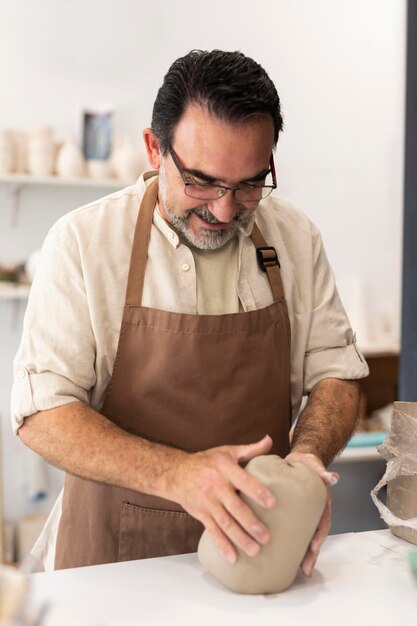 Uomo sorridente del tiro medio che tiene argilla