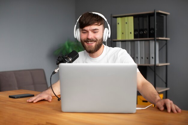 Uomo sorridente di colpo medio che registra podcast all'interno