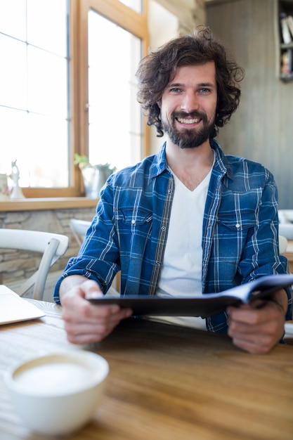 Uomo sorridente di menu tenendo in caffetteria