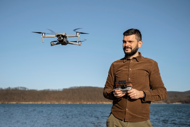Uomo sorridente di tiro medio con drone all'aperto
