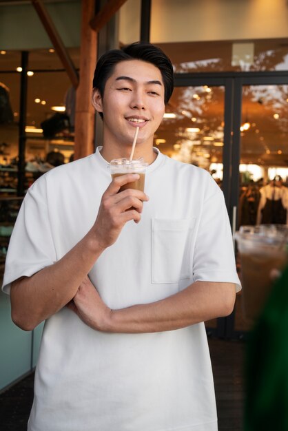 Uomo sorridente di vista frontale con caffè freddo