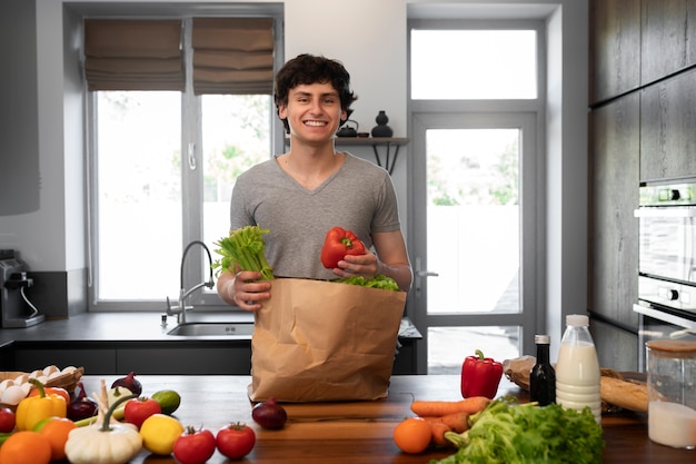 Uomo sorridente di vista frontale con generi alimentari