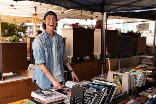 Uomo sorridente di vista laterale al mercato delle pulci