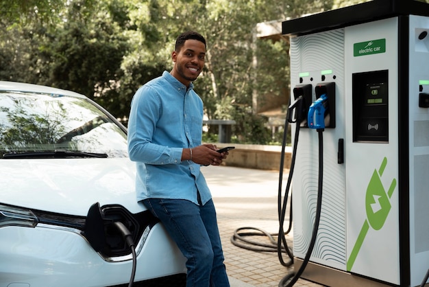 Uomo sorridente di vista laterale che aspetta l'auto per caricare