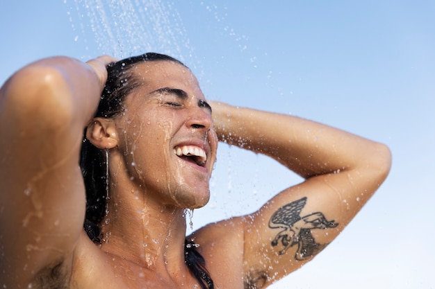 Uomo sorridente di vista laterale che fa la doccia