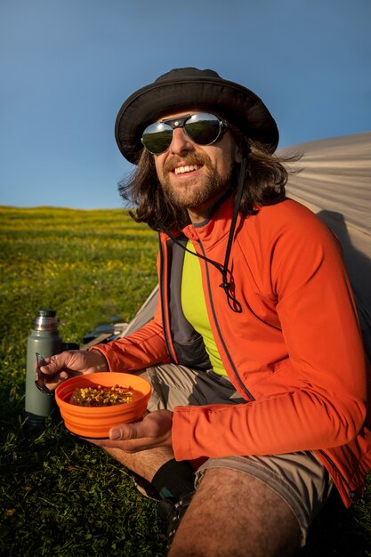 Uomo sorridente di vista laterale che mangia all'aperto