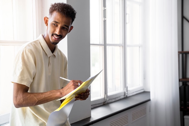 Uomo sorridente di vista laterale che prende appunti