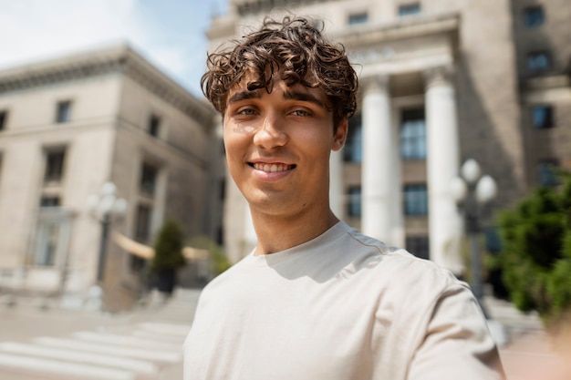 Uomo sorridente di vista laterale che prende selfie fuori