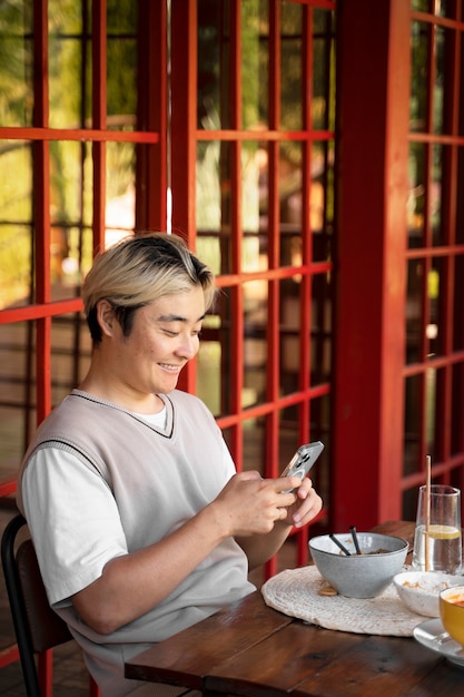 Uomo sorridente di vista laterale che tiene smartphone