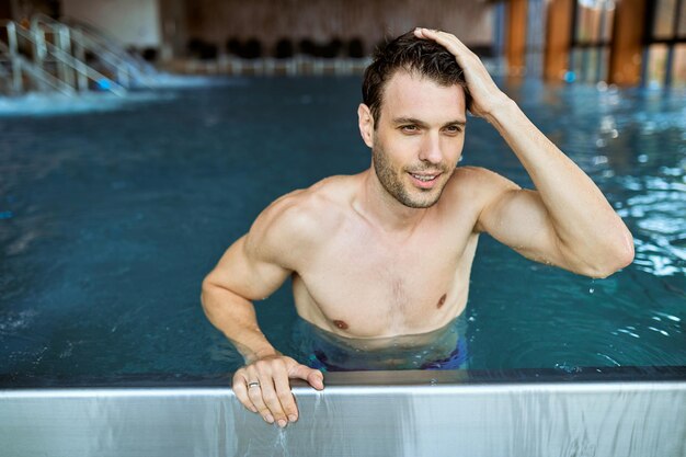 Uomo sorridente godendo in piscina coperta in vacanza