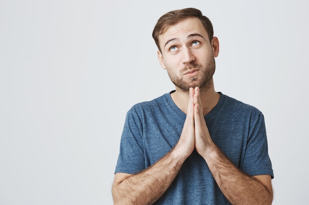 Uomo sorridente promettente che esprime desiderio, pregando Dio