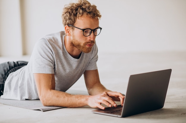 Uomo sportivo che guarda tutorial e pratica yoga sul tappetino