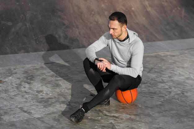 Uomo sportivo che riposa su una pallacanestro