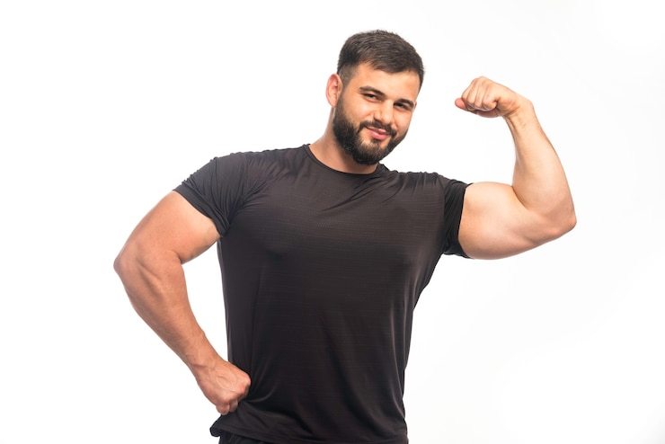 Foto gratuito uomo sportivo in camicia nera che mostra i muscoli delle braccia.