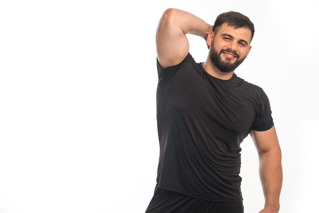 Uomo sportivo in camicia nera che mostra il suo muscolo tricipite