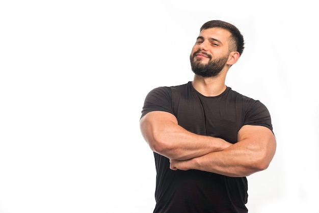 Uomo sportivo in camicia nera chiudendo i muscoli del braccio.