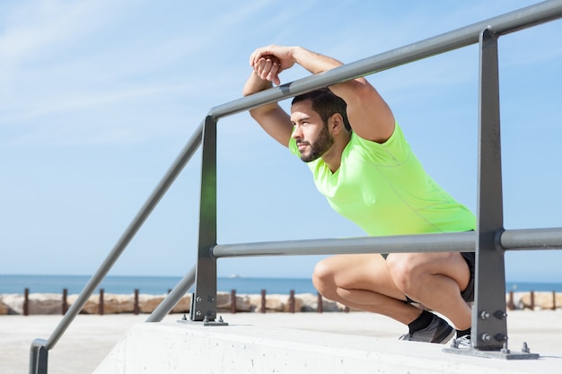 Uomo sportivo rilassato seduto e appoggiato alla ringhiera