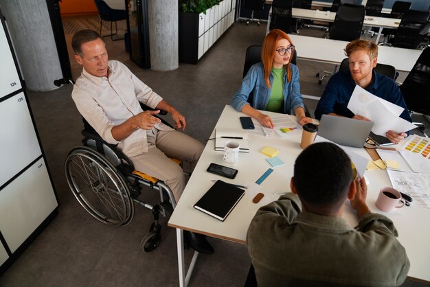 Uomo su una sedia a rotelle che ha un lavoro d'ufficio inclusivo