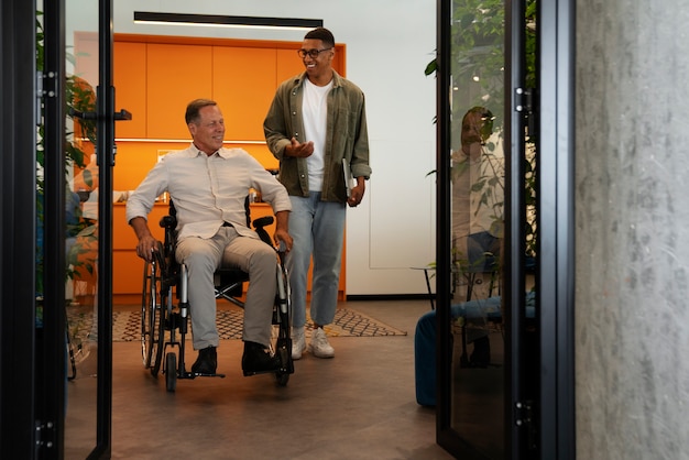 Uomo su una sedia a rotelle che ha un lavoro d'ufficio inclusivo