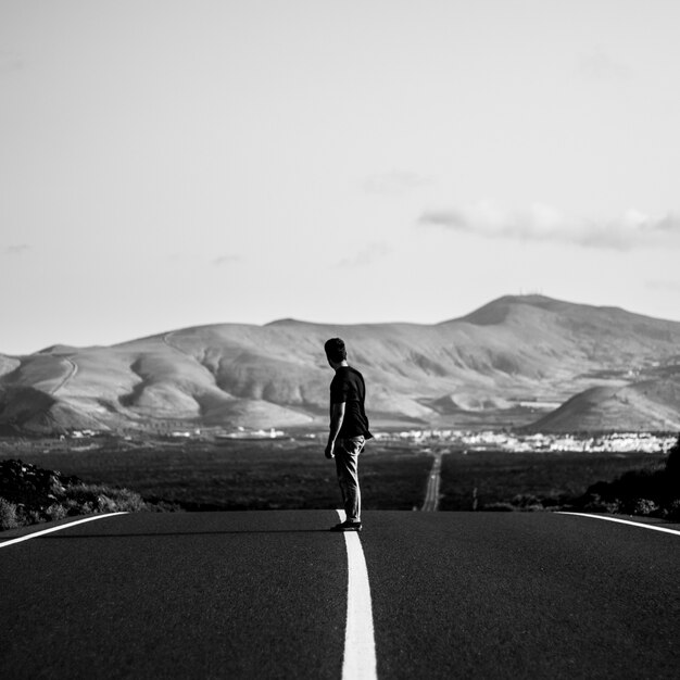 Uomo su uno skateboarder in sella su una strada statale vuota con incredibili colline