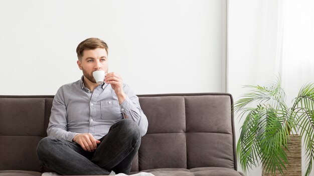 Uomo sul divano a bere il caffè