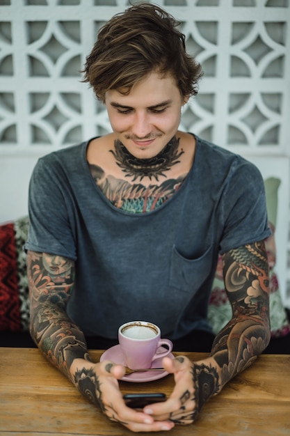 uomo tatuato che beve caffè in un caffè