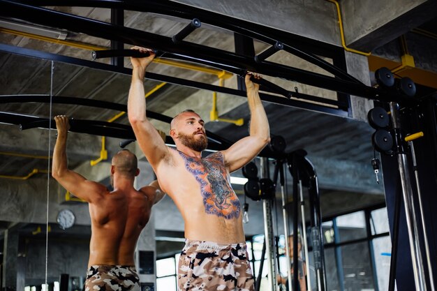 Uomo tatuato in forma facendo esercizi in palestra