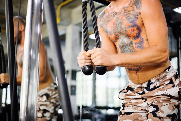 Uomo tatuato in forma facendo esercizio in palestra