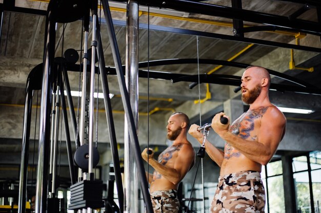 Uomo tatuato in forma facendo esercizio in palestra