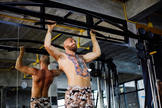 Uomo tatuato in forma facendo esercizio in palestra