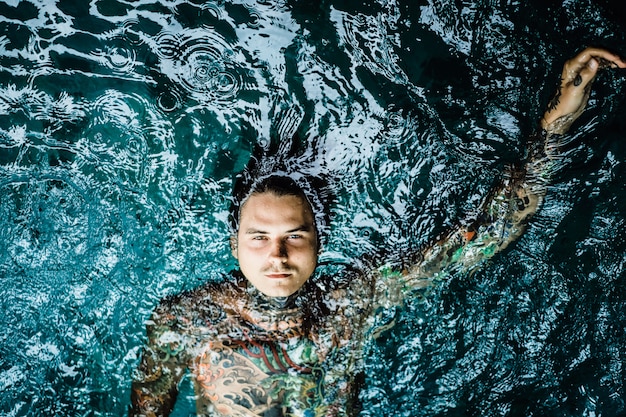 uomo tatuato nella piscina sotto la pioggia.