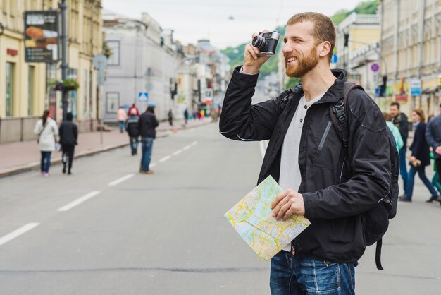 Uomo turistico con la mappa e la macchina fotografica