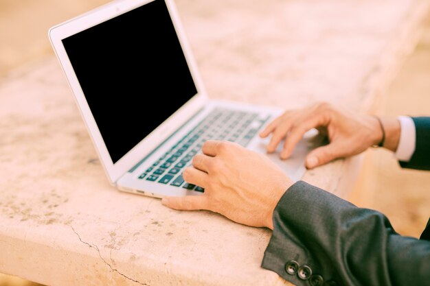 Uomo vestito che lavora con un piccolo computer portatile