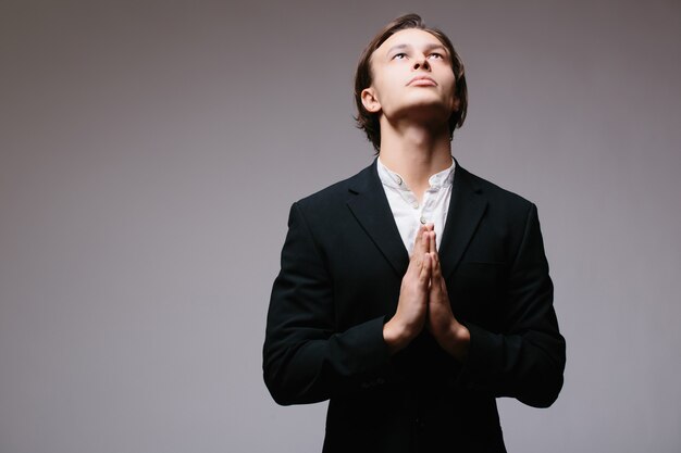 Uomo vestito in posizione di preghiera devota isolato su grigio