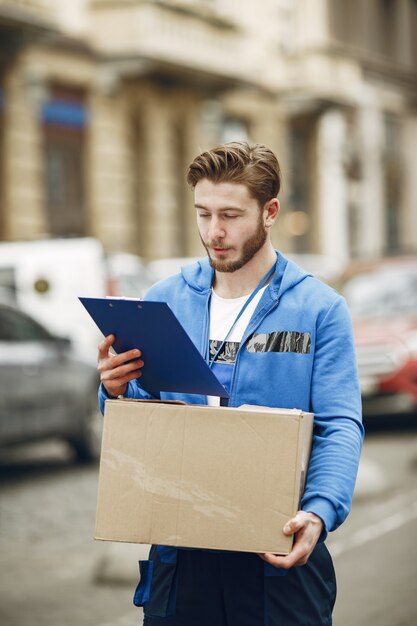 Uomo vicino al camion. Ragazzo in uniforme da consegna. Uomo con appunti.