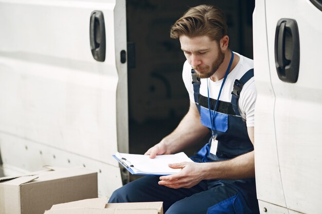 Uomo vicino al camion. Ragazzo in uniforme da consegna. Uomo con appunti.