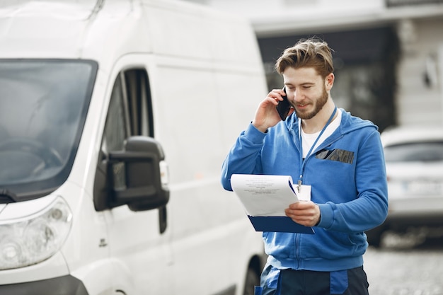 Uomo vicino al camion. Ragazzo in uniforme da consegna. Uomo con appunti.