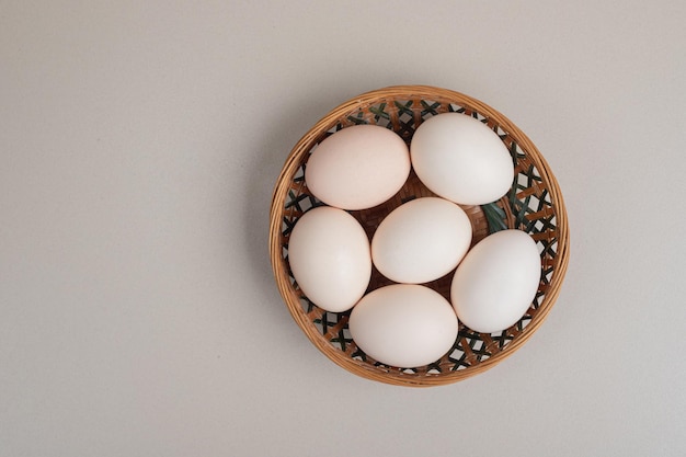 Uova bianche del pollo fresco sul canestro di vimini.