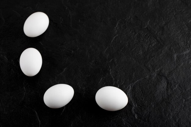 Uova bianche fresche sulla superficie nera