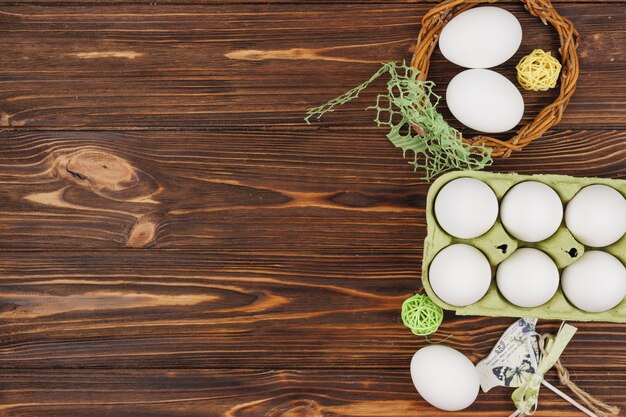 Uova bianche in scaffale con piccolo uccello e palle di legno sul tavolo
