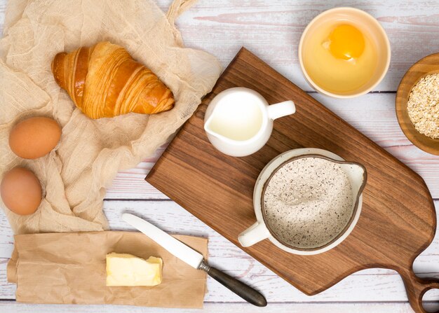 Uova; croissant; burro; latte; crusca di farina e avena sulla scrivania in legno