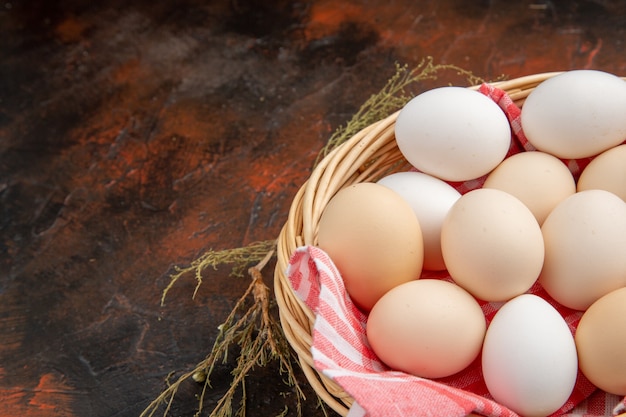 Uova di gallina bianca vista frontale all'interno del cesto con asciugamano sulla superficie scura dark