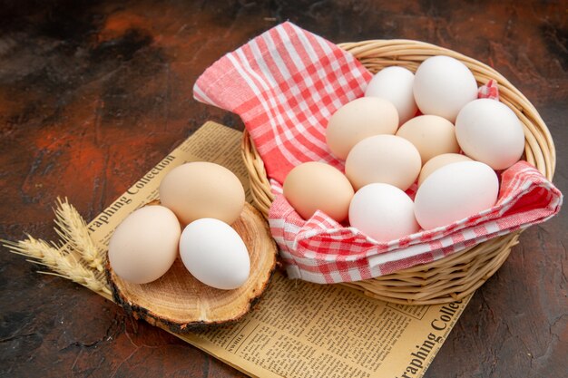Uova di gallina bianca vista frontale all'interno del cesto su superficie scura